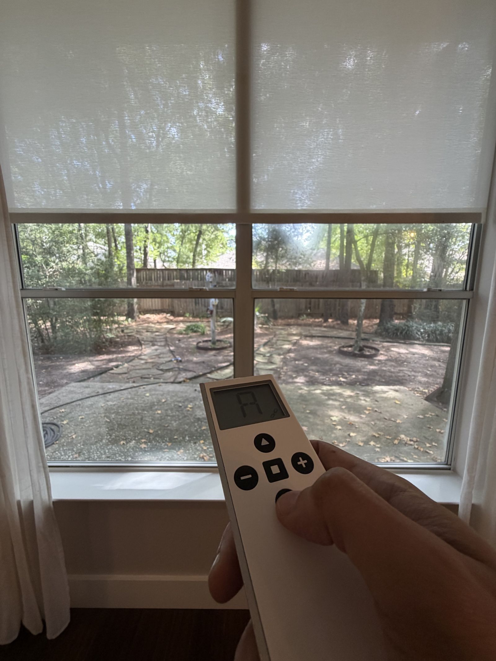Hand holding an Automate remote control to operate a motorized roller shade