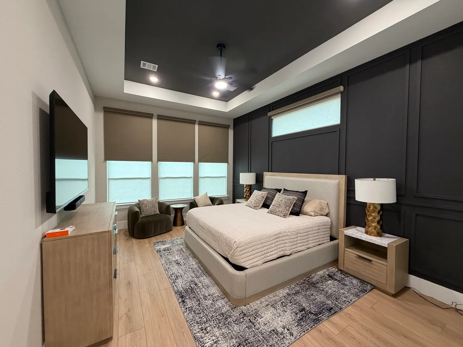 Primary bedroom in Willis, Texas, with brown outside-mounted blackout roller shades partially lowered over white light-filtering shades