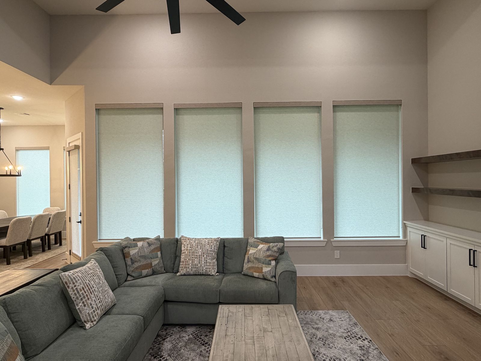 Cordless light-filtering roller shades across four living-room windows.