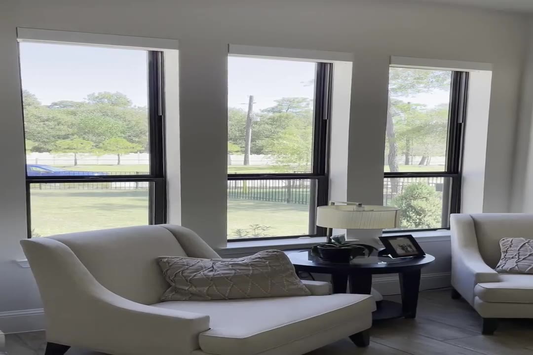 Motorized roller shades lowering over tall living room windows