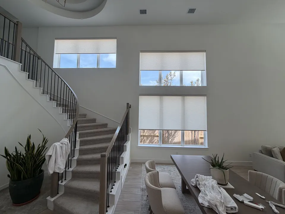 Motorized roller shades halfway lowered across tall staircase windows in Conroe, Texas