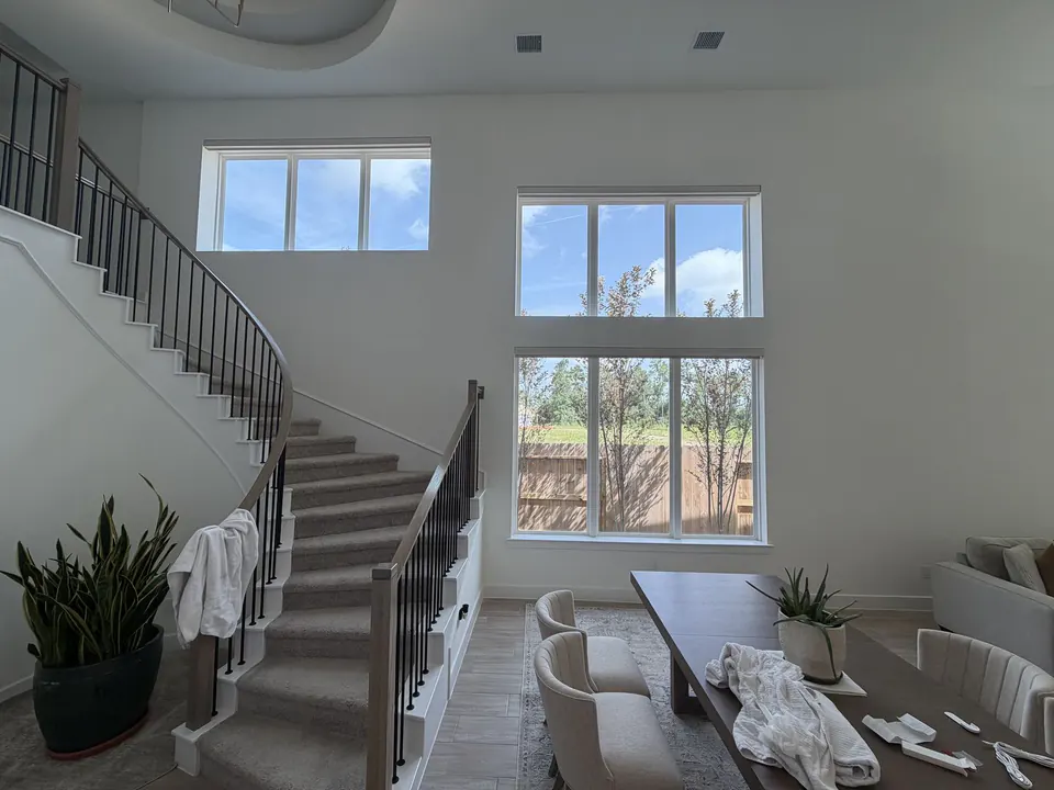 Motorized roller shades open across tall staircase windows in Conroe, Texas