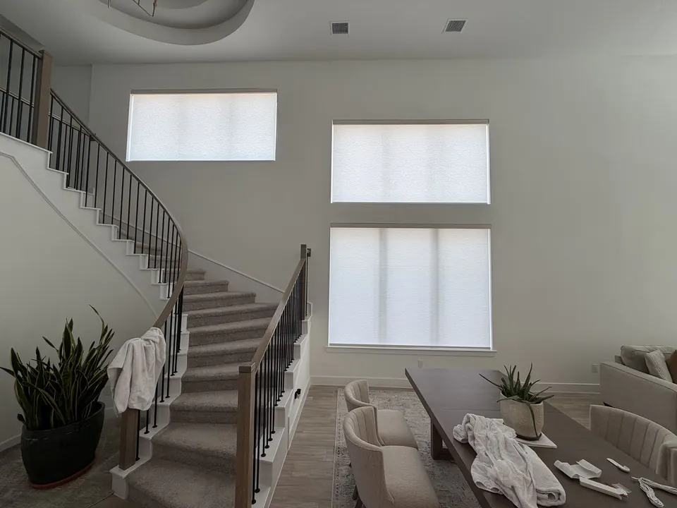 Motorized roller shades fully closed across tall staircase windows in Conroe, Texas