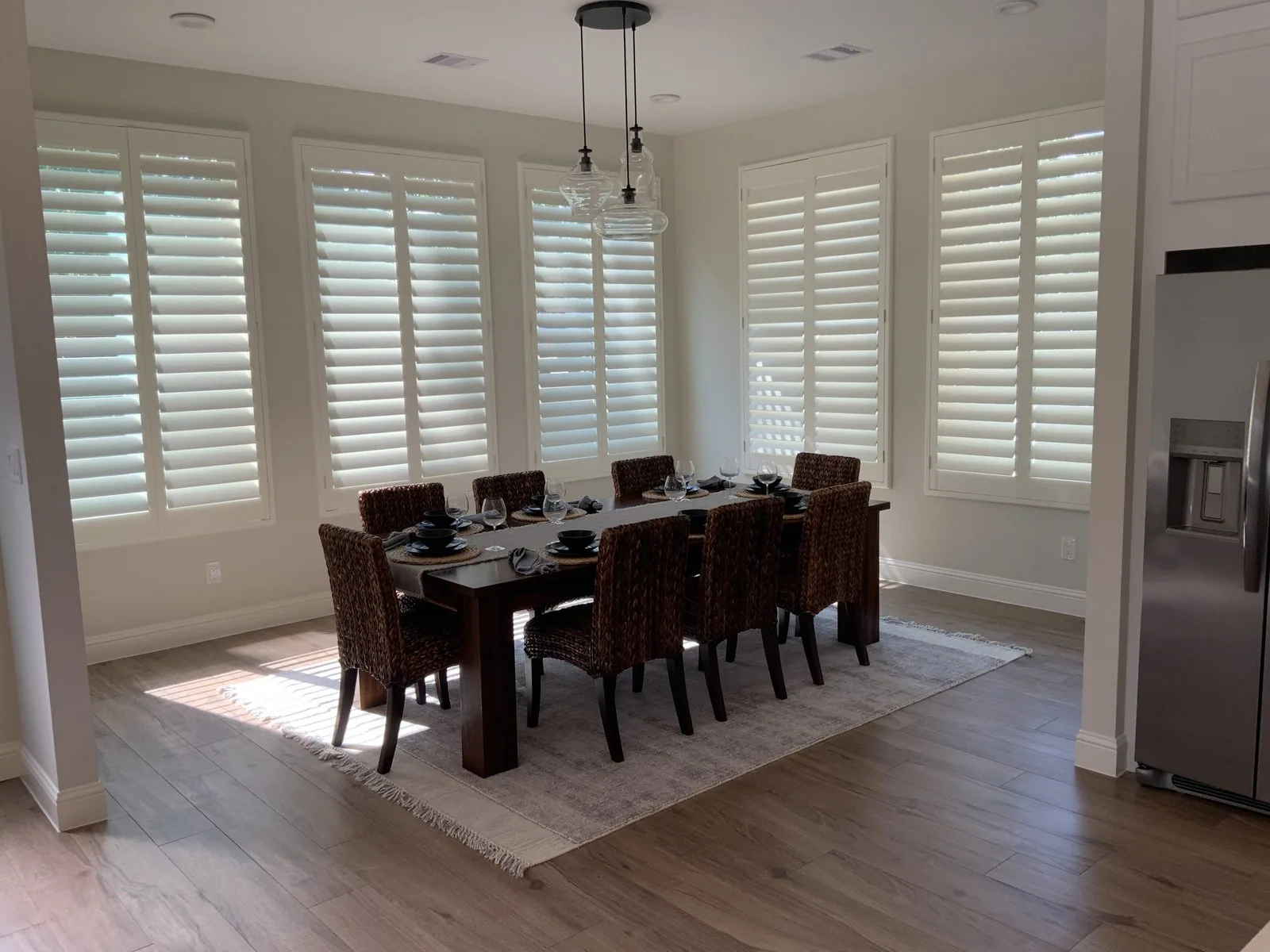 White plantation shutters with louvers tilted open across a dining room in Tomball, TX