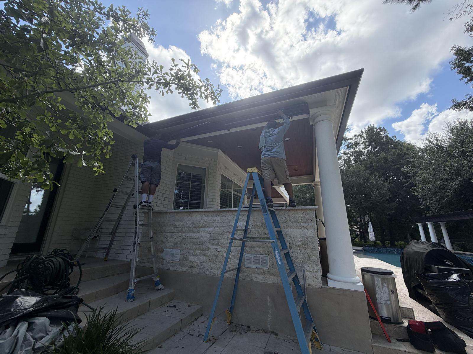 Starlite installers mounting a retractable awning under a covered patio.
