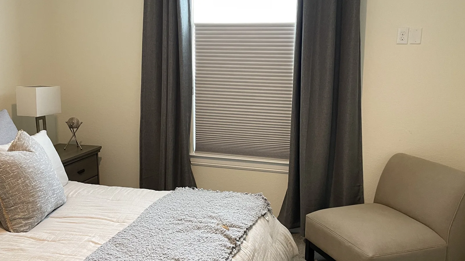 Gray top-down bottom-up honeycomb shade installed between bedroom curtains