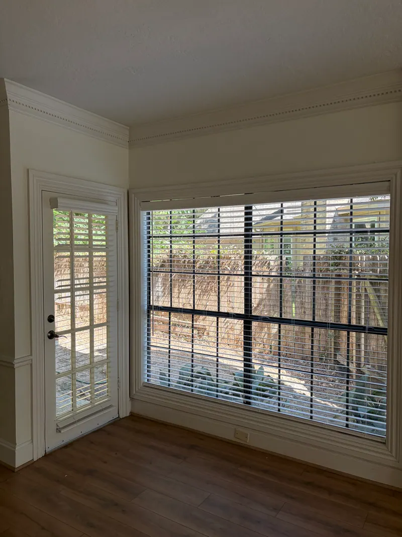 White faux wood blinds across living-room windows.