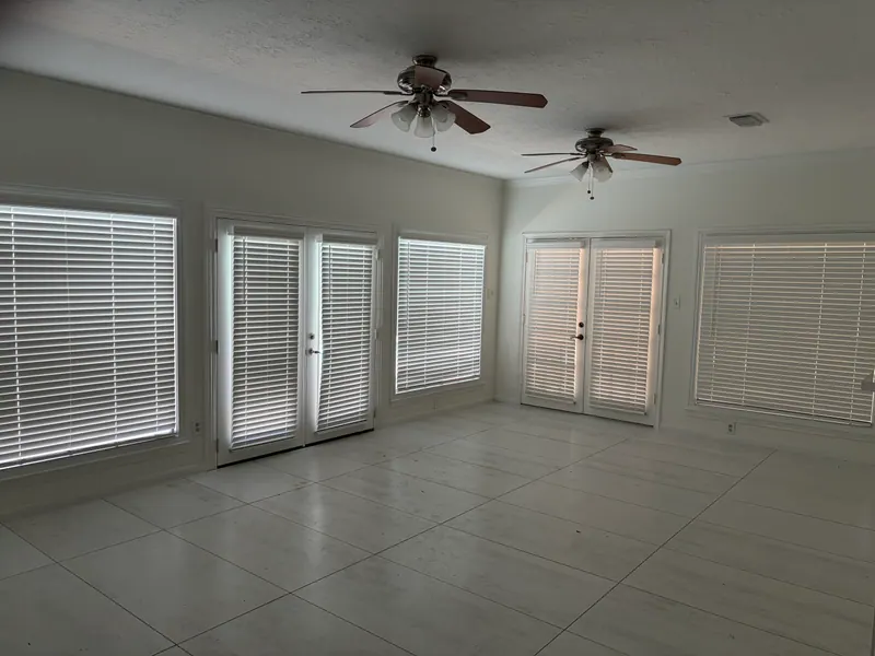 White faux wood blinds beside a terrace sitting area.