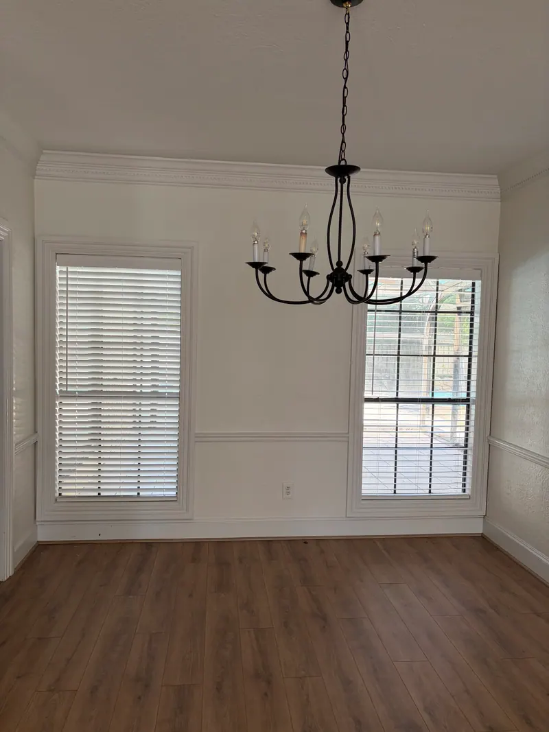 White faux wood blinds on dining-room windows.