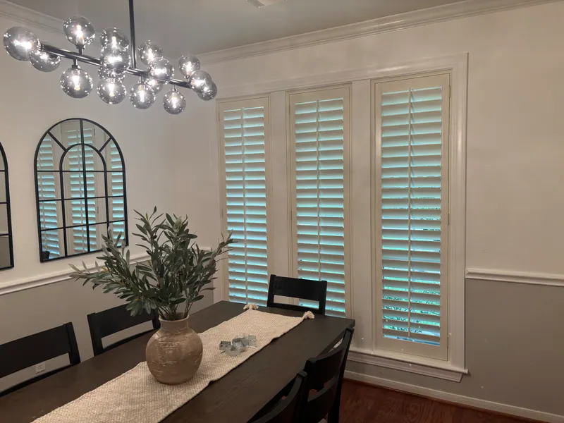 White plantation shutters beside a dining table.
