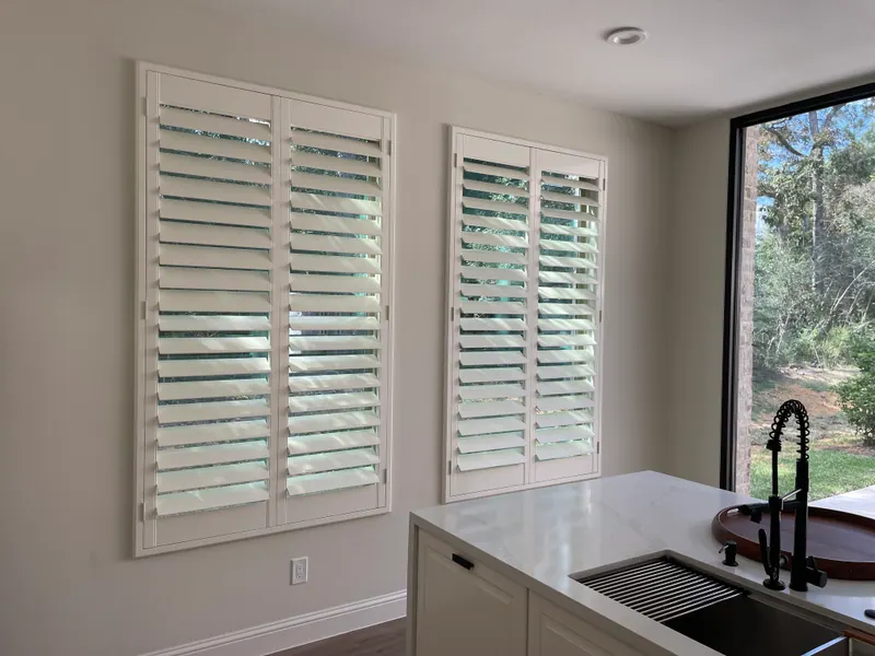 White plantation shutters covering a kitchen window.