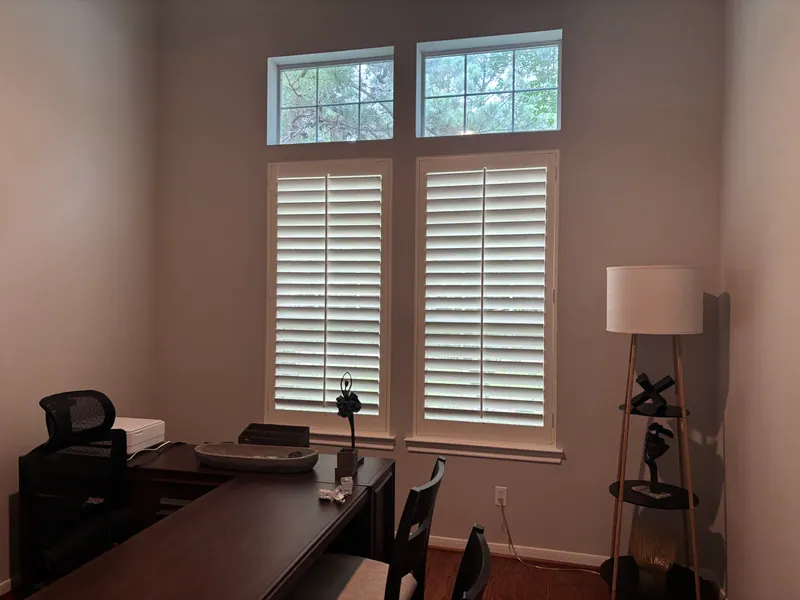 White plantation shutters on windows in a home office.