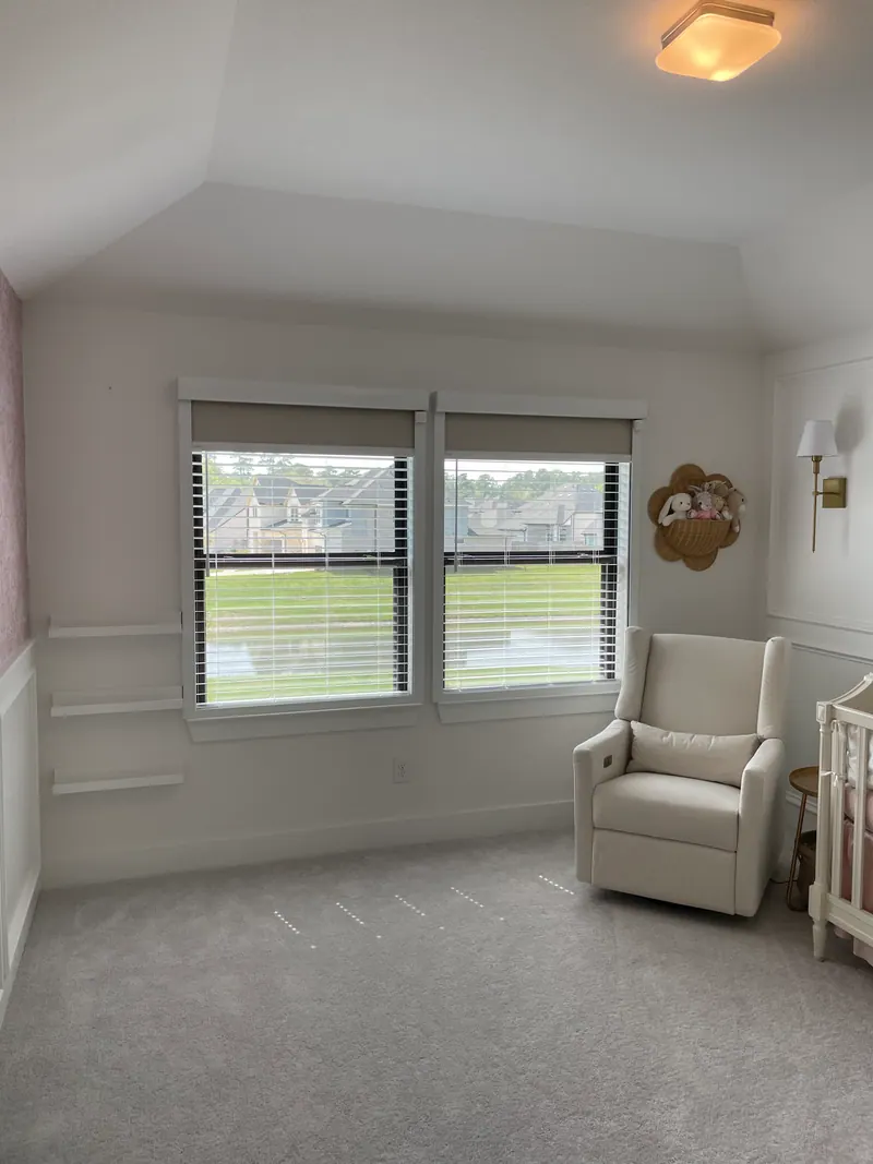 Roller shade above horizontal blinds in a nursery.