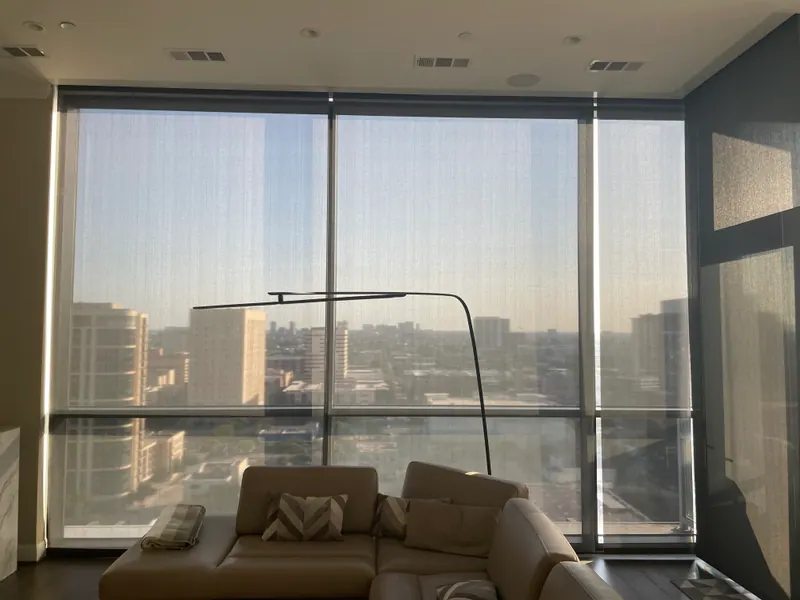 Roller shades covering living-room windows beside a skyline view.
