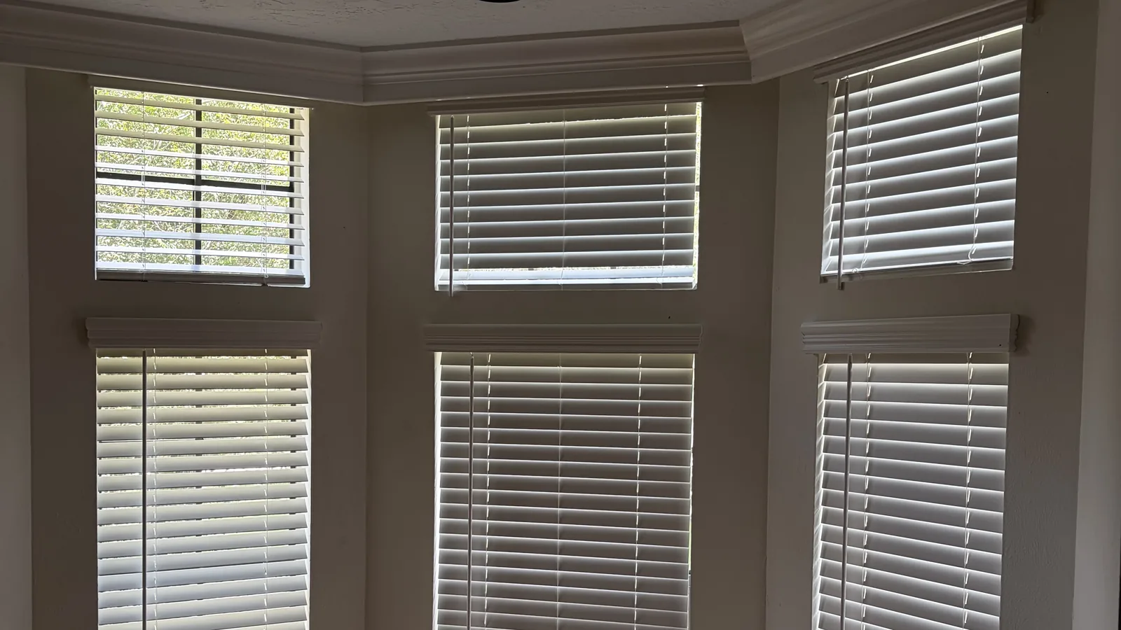 Six white faux wood blinds installed across upper and lower bay windows